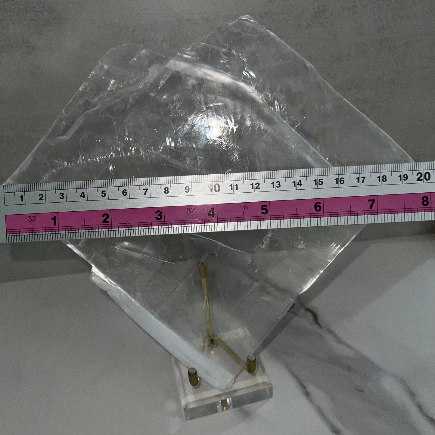 Metallic object on a gray surface with a ruler for scale