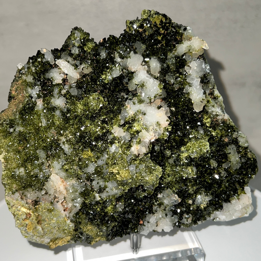 Mineral sample with green and white crystals on a gray background
