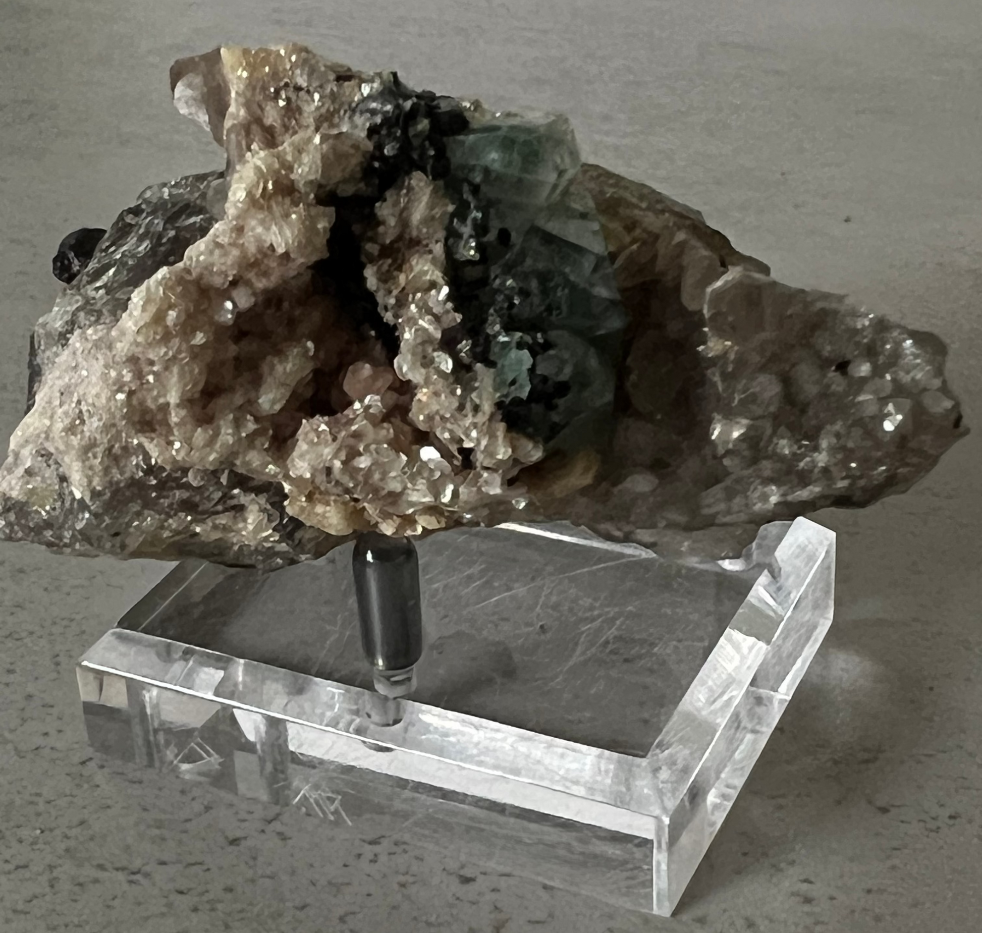 Mineral specimen on a clear acrylic stand against a neutral background