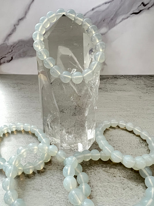 Set of beaded bracelets on a marble surface with a crystal tower.