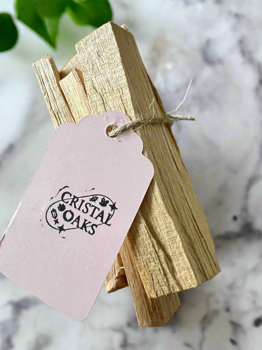 Wooden sticks tied together with a pink tag labeled 'Cristal Oaks' on a marble surface.