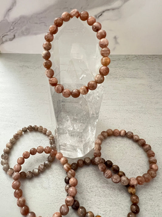 Beaded bracelets on a light gray surface with a crystal in the background