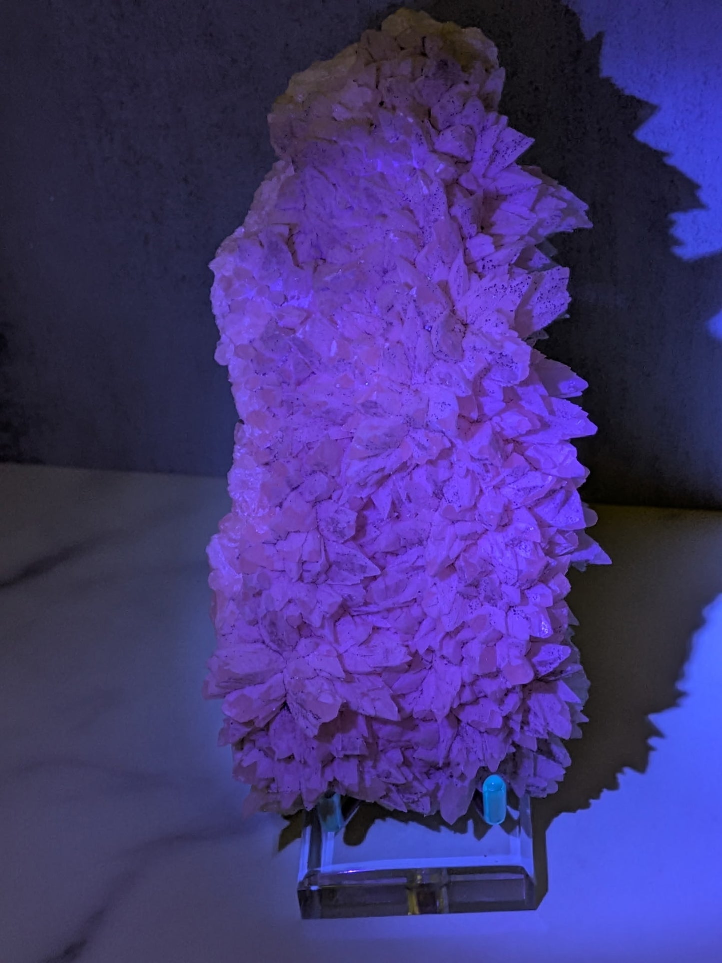 Pink crystal formation under purple light on a dark background