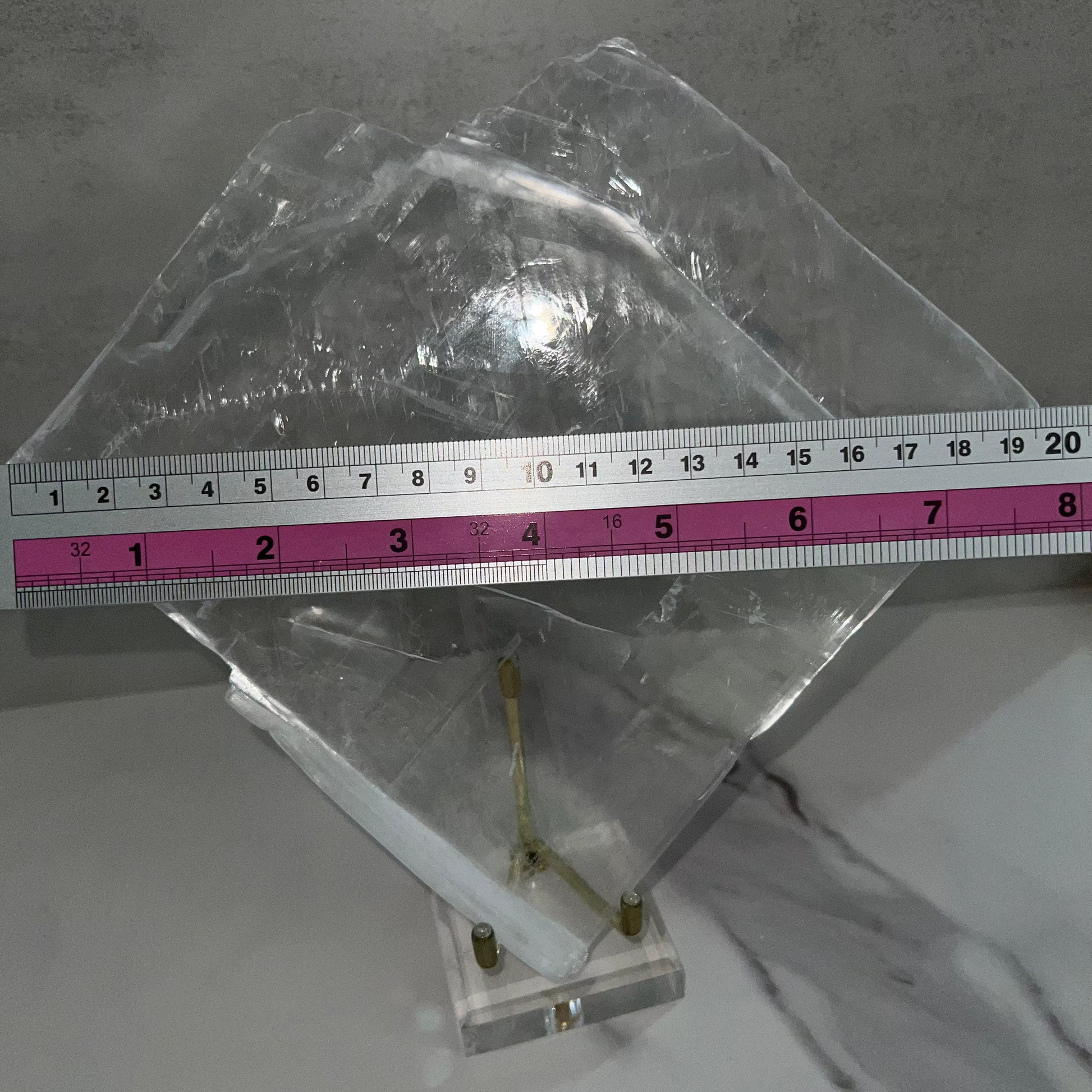 Metallic object on a gray surface with a ruler for scale